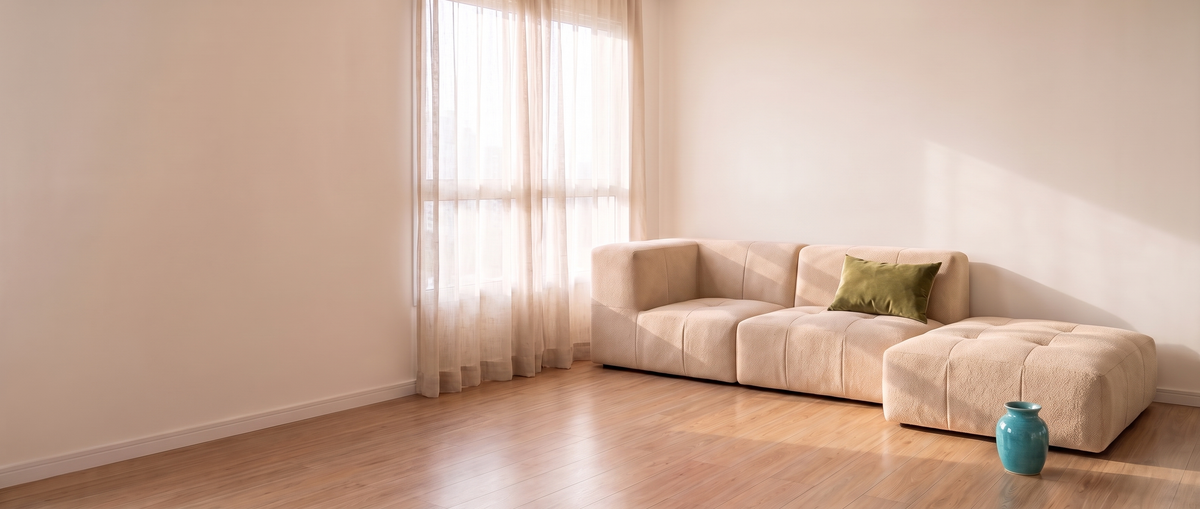 Sofá Lótus em bouclé bege numa sala clara, com piso de madeira e almofada verde